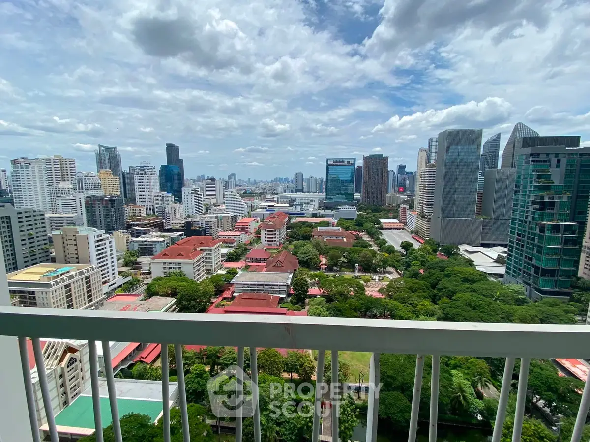 Stunning cityscape view from a high-rise balcony overlooking urban skyline and lush greenery.