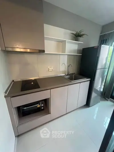 Modern kitchen with sleek cabinetry, built-in oven, and stainless steel appliances in a bright, compact space.