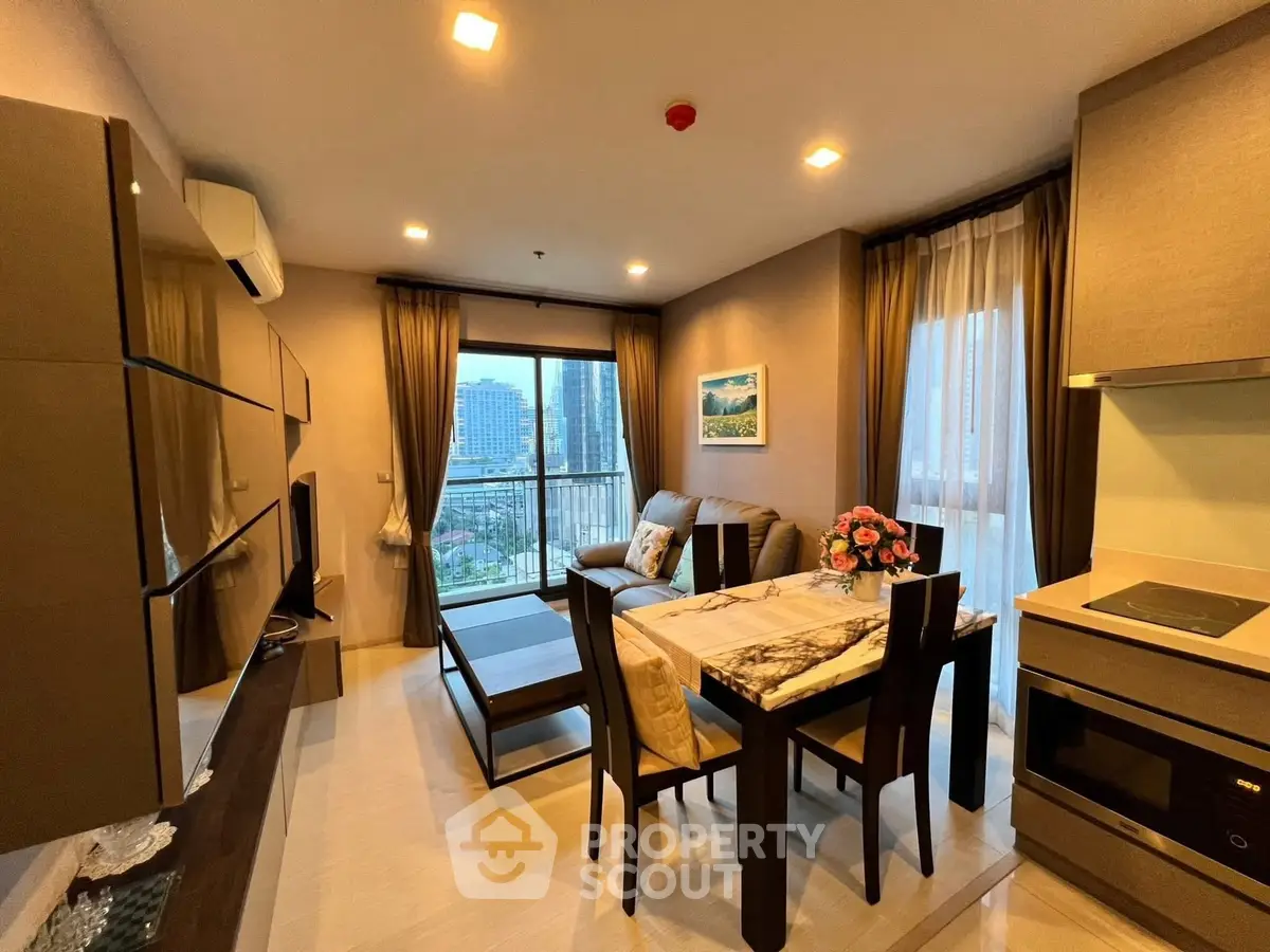 Modern living room with open kitchen and city view, featuring elegant decor and ample natural light.