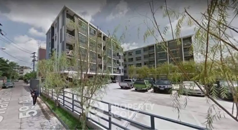 Modern apartment building with spacious parking area and lush greenery