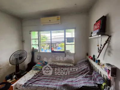 Cozy bedroom with air conditioning and window view, featuring a bed and fan for comfort.