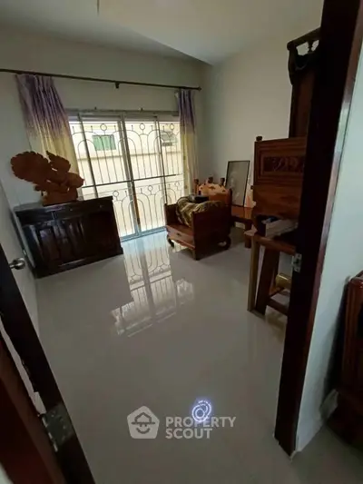 Cozy bedroom with polished floors and elegant wooden furniture, featuring a large window with decorative curtains.
