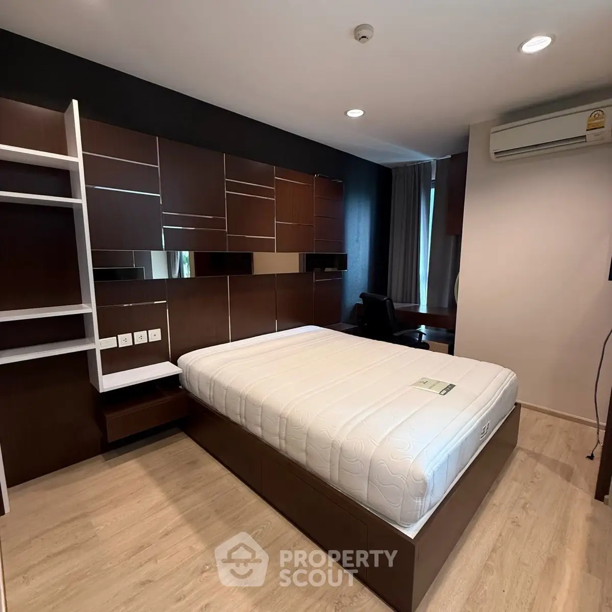 Modern bedroom with sleek wooden furniture and air conditioning, perfect for comfort and style.