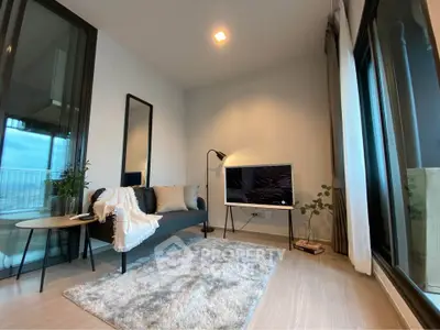 Modern living room with cozy decor and large windows offering natural light.