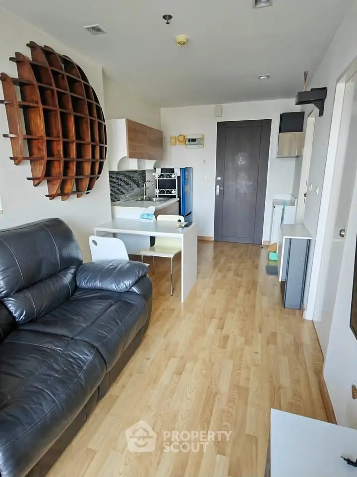 Modern living room with stylish decor and open kitchen layout, featuring wooden flooring and contemporary furniture.