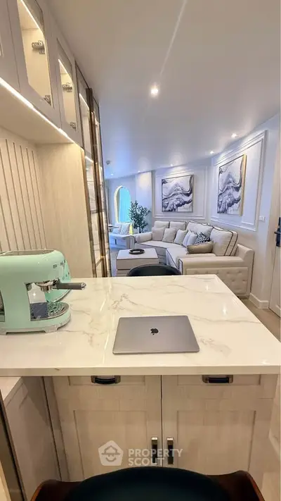 Luxurious open-plan living room with modern decor and stylish furniture, featuring a sleek kitchen counter and espresso machine.