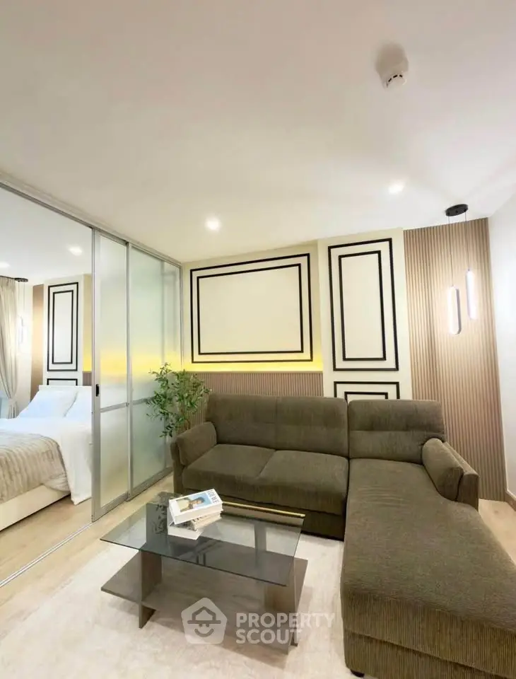 Modern living room with stylish decor and glass partition to bedroom