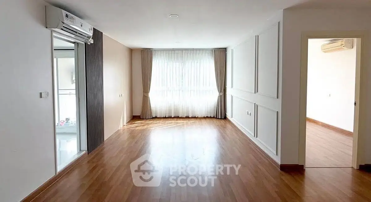 Spacious empty living room with wooden flooring and large window