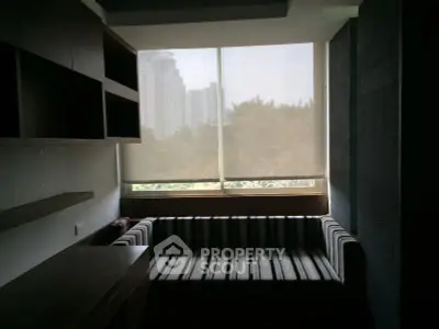 Cozy living room with striped sofa and large window offering city view.