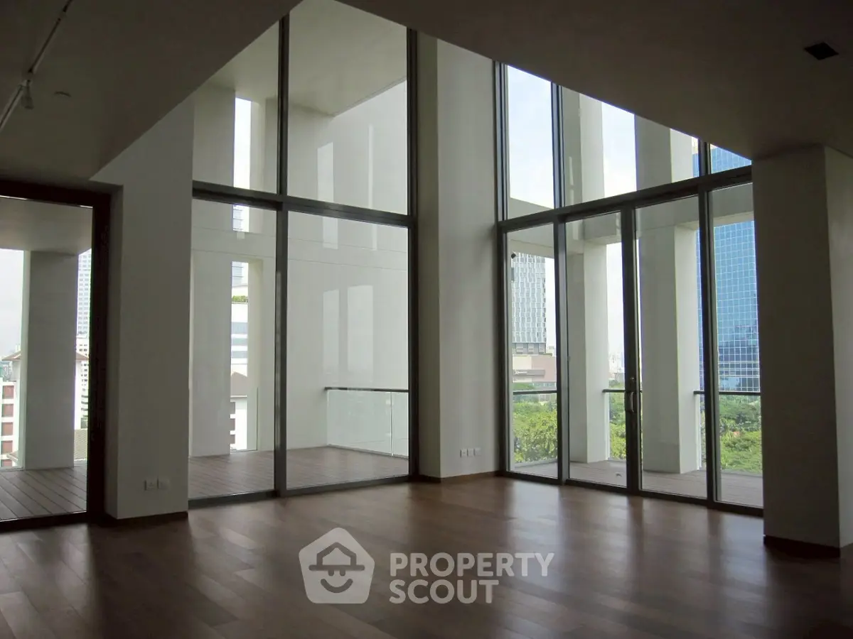 Spacious modern living room with floor-to-ceiling windows and stunning city view.