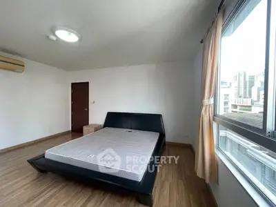 Spacious bedroom with city view and modern furnishings in a high-rise apartment.