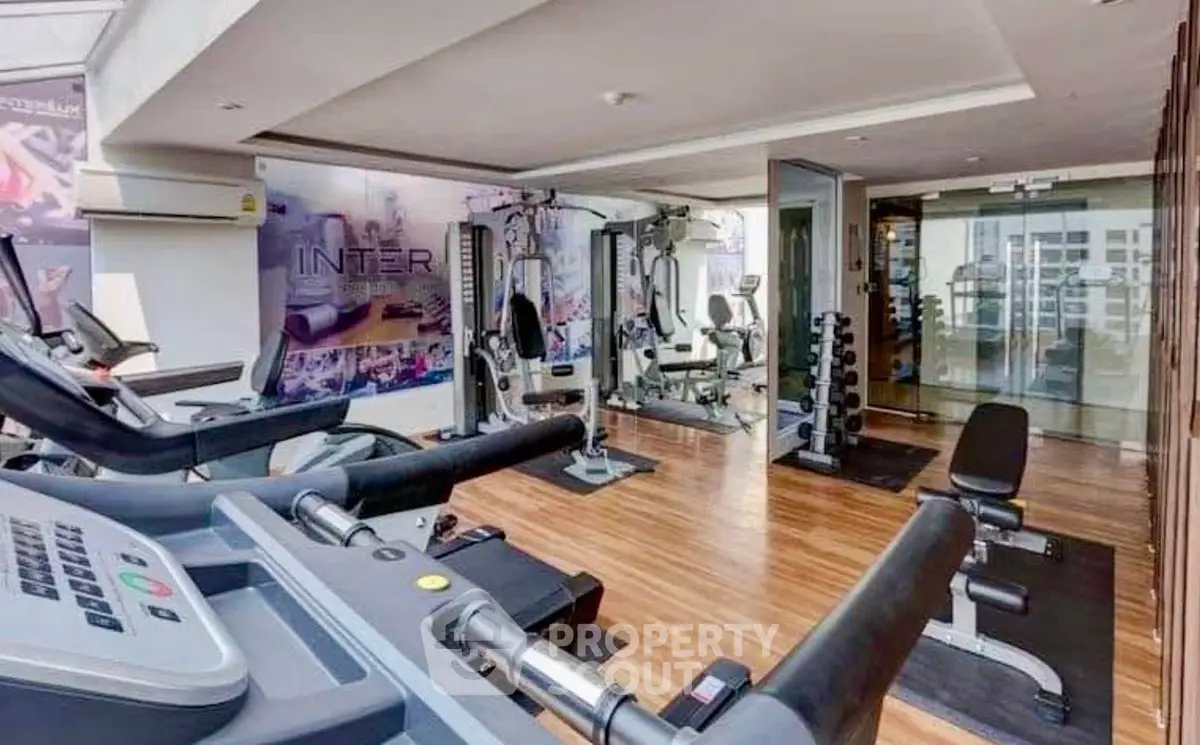 Modern gym with state-of-the-art equipment and wooden flooring in a luxury residential building.
