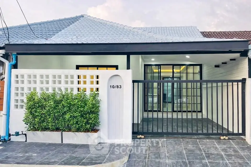 Charming modern house exterior with gated entrance and lush greenery.