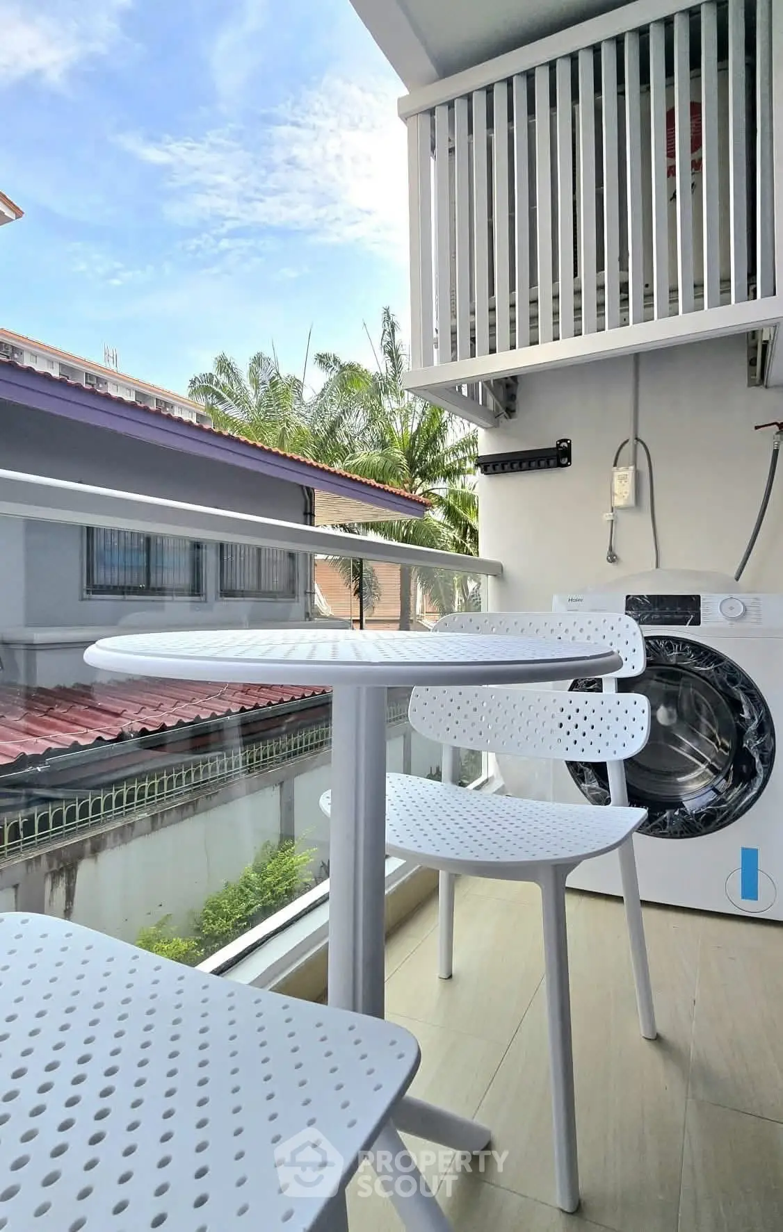 Charming balcony with modern furniture and washing machine, perfect for relaxation and convenience.