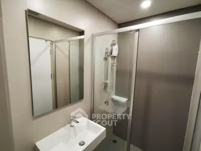 Modern bathroom with sleek shower and stylish sink in contemporary apartment.