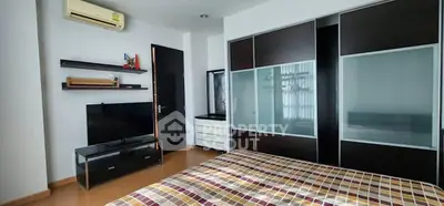Modern bedroom with sleek furniture and ample storage space, featuring a stylish air conditioner and contemporary decor.