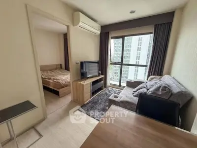 Modern living room with cozy sofa and large window offering city view, adjacent to a bedroom.