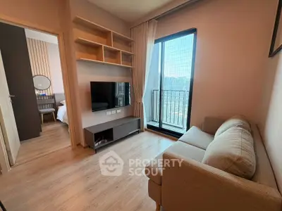 Modern living room with cozy sofa and TV, featuring a view of the city skyline through large windows.