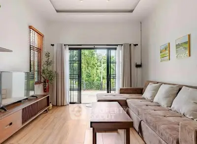 Spacious living room with modern decor and large windows opening to a lush garden view.