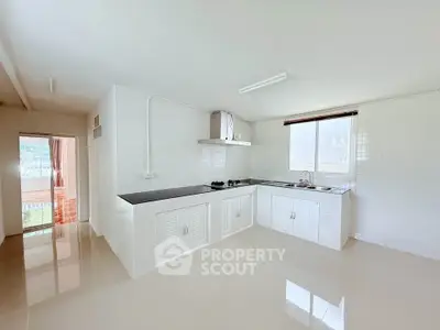 Spacious kitchen with sleek white cabinetry and modern gas stove, offering ample natural light and open layout.