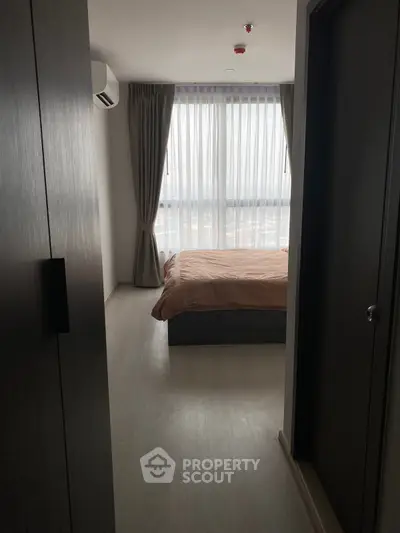 Cozy bedroom with large window and modern furnishings, offering a serene and inviting atmosphere.