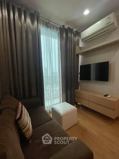 Cozy living room with modern decor, featuring a plush sofa, wall-mounted TV, and air conditioning.