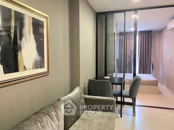 Modern apartment interior with cozy living area and stylish bedroom separated by glass partition.