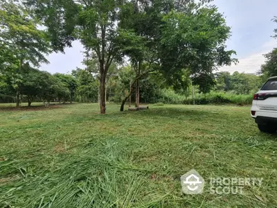 Lush green land parcel with mature trees, ideal for a serene home build, located in a tranquil neighborhood with ample space for landscaping.