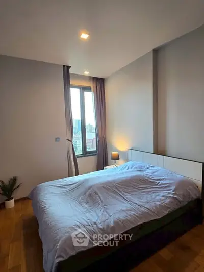 Cozy bedroom with city view, featuring a large bed and modern decor.