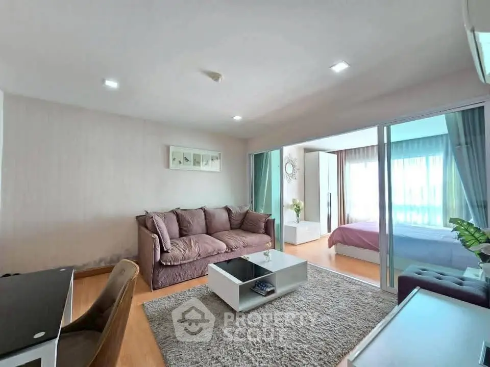 Spacious modern living room with cozy sofa and elegant decor, adjacent to a bright bedroom.