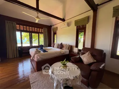 Luxurious bedroom with stunning view, elegant furnishings, and cozy seating area in a serene setting.
