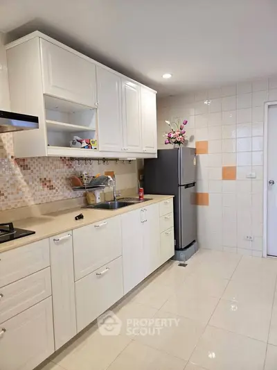 Modern kitchen with sleek cabinets and stainless steel fridge in a bright, tiled space.