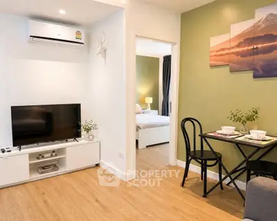 Modern living room with TV, air conditioning, and dining area leading to a cozy bedroom.