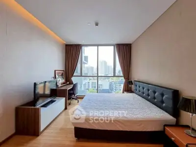 Spacious bedroom with city view, modern furniture, and natural light.