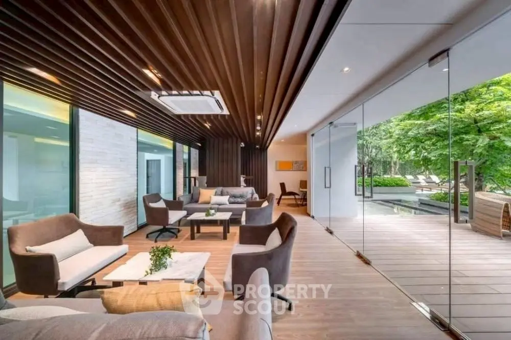 Luxurious modern living room with floor-to-ceiling glass doors opening to a serene garden view.