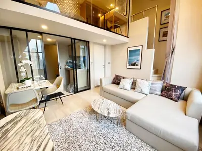 Luxurious modern living room with mezzanine, elegant decor, and open dining area in a stylish apartment.