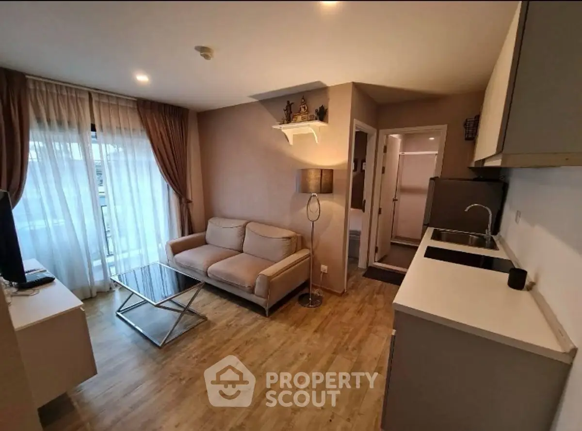 Modern living room with cozy sofa and open kitchen layout, featuring stylish decor and natural light.