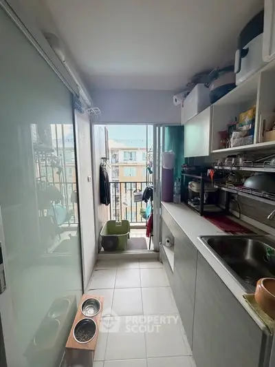 Compact kitchen with open shelving and balcony access in urban apartment