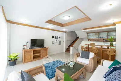 Spacious living room with modern decor and open layout, featuring a cozy seating area and stylish staircase.