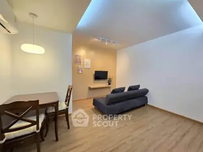 Modern living room with cozy sofa and dining area, featuring stylish lighting and wooden flooring.