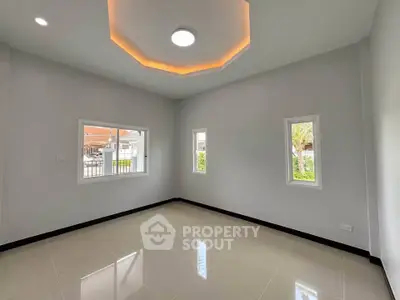 Spacious empty room with modern ceiling light and large windows in a new home.
