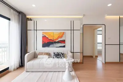 Modern living room with stylish decor and large windows offering natural light and city views.