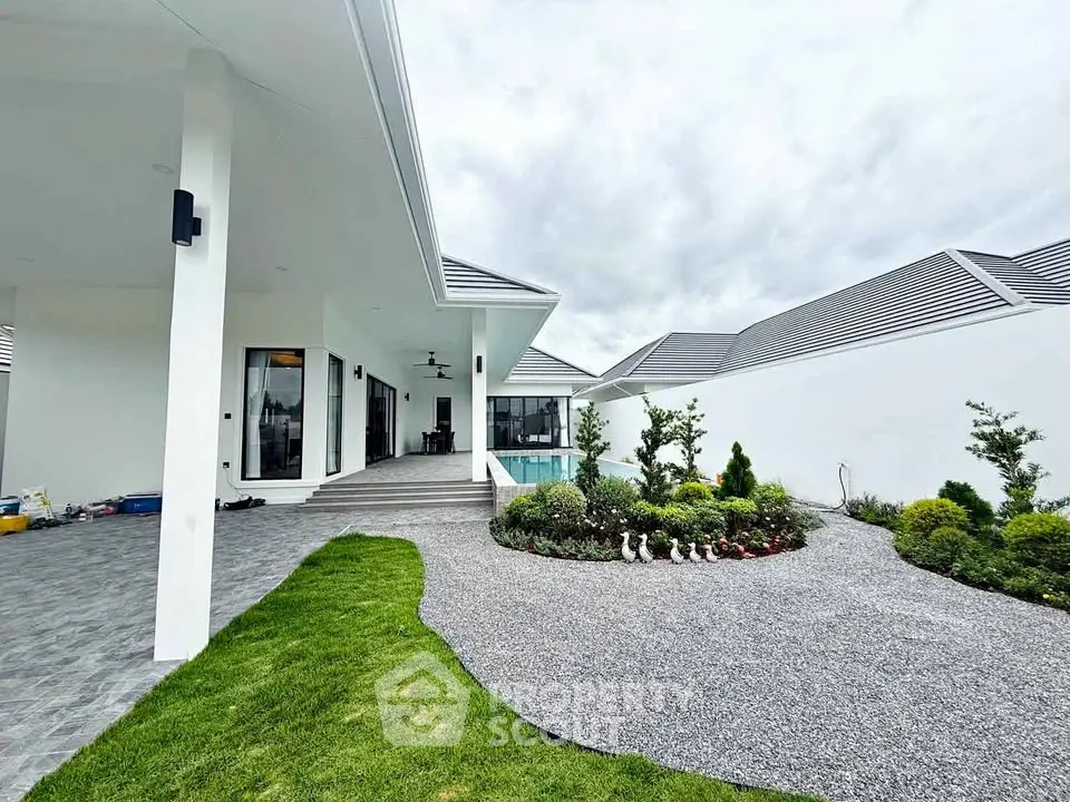 Luxurious modern home with sleek architecture and lush garden, featuring a private pool and spacious outdoor area.