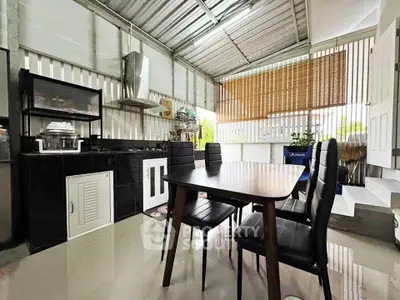 Modern kitchen with dining area and sleek black furniture in open layout.