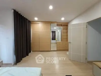 Spacious bedroom with modern wooden wardrobe and ample lighting