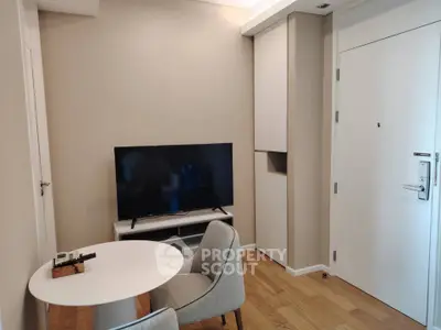 Modern apartment interior with TV, dining table, and elegant chairs on wooden flooring.