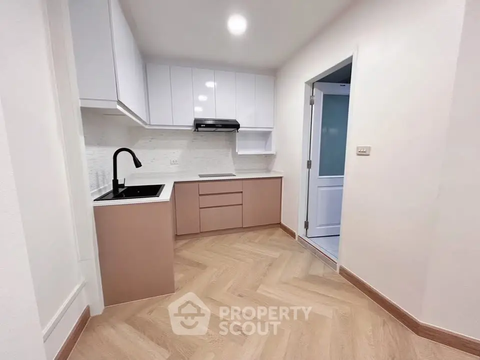 Modern kitchen with sleek cabinetry and herringbone flooring in a stylish apartment.