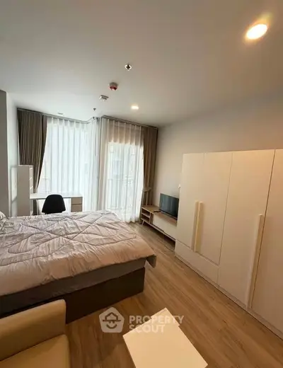 Modern bedroom with large window, stylish furniture, and cozy ambiance.