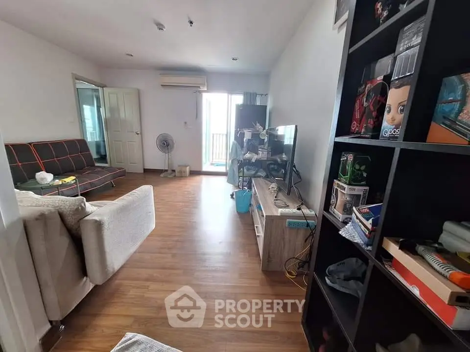 Spacious living room with modern decor and wooden flooring, featuring a cozy sofa and entertainment unit.