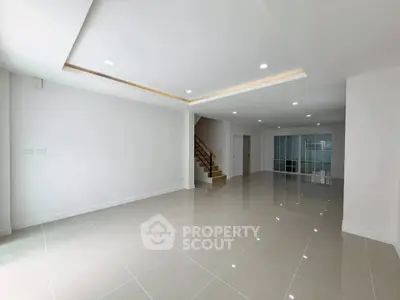 Spacious modern living room with glossy tiled floors and recessed lighting, perfect for family gatherings.